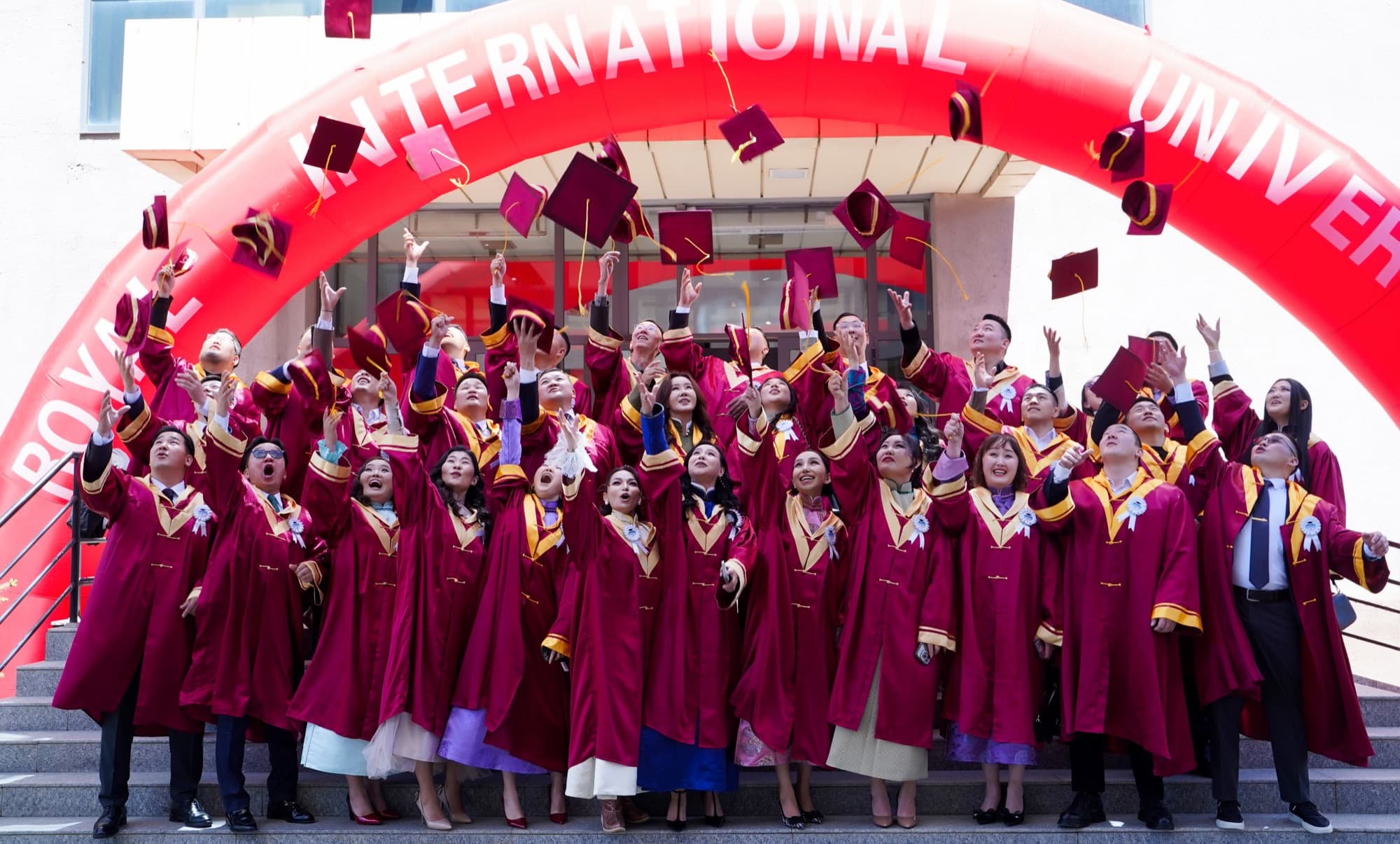 Graduates celebrate under the Royal International University arch